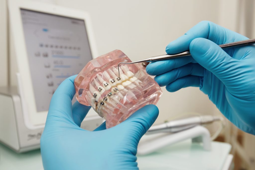 Prosthetics hands while working on the denture, false teeth, a study and a table with dental tools. Dental laboratory.