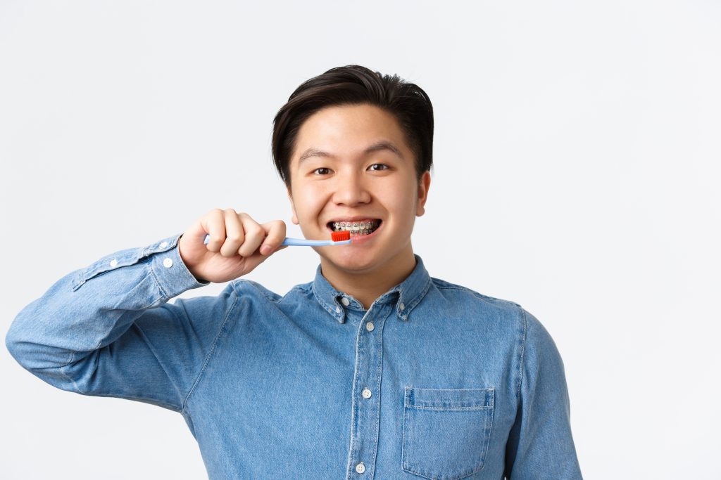 man wearing adult braces holding a tooth brush